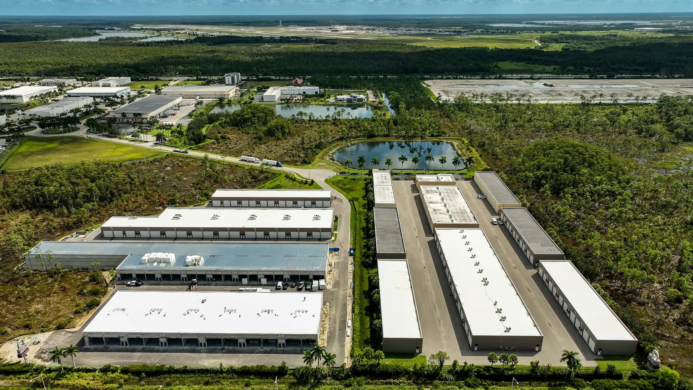 High overhead aerial of the campus with the lake, the entrance road and the surrounding industrial park.