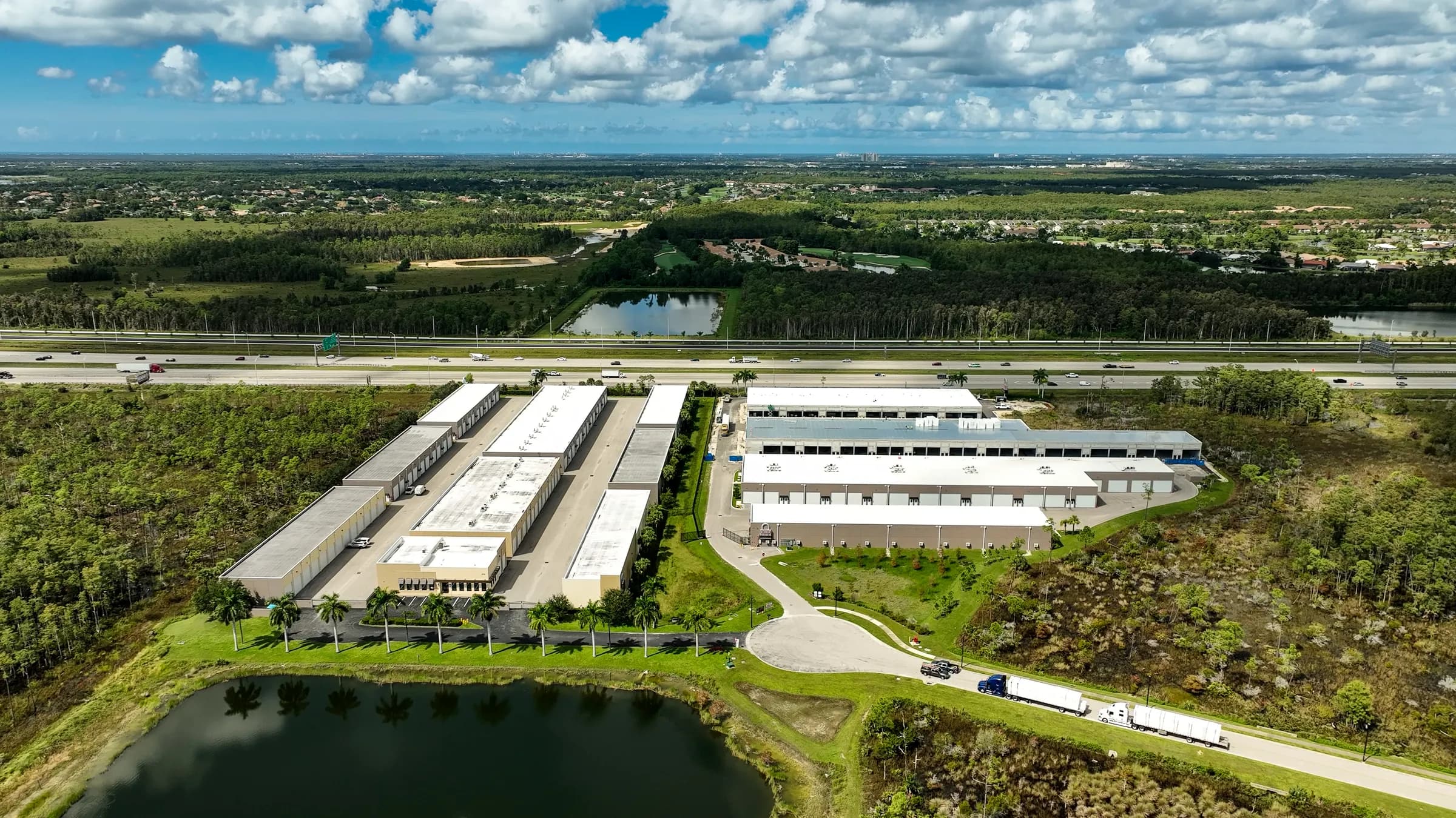 Wide aerial of Vehicle Fortress from the lake side, with the entrance drive, the building rows and I-75 beyond.