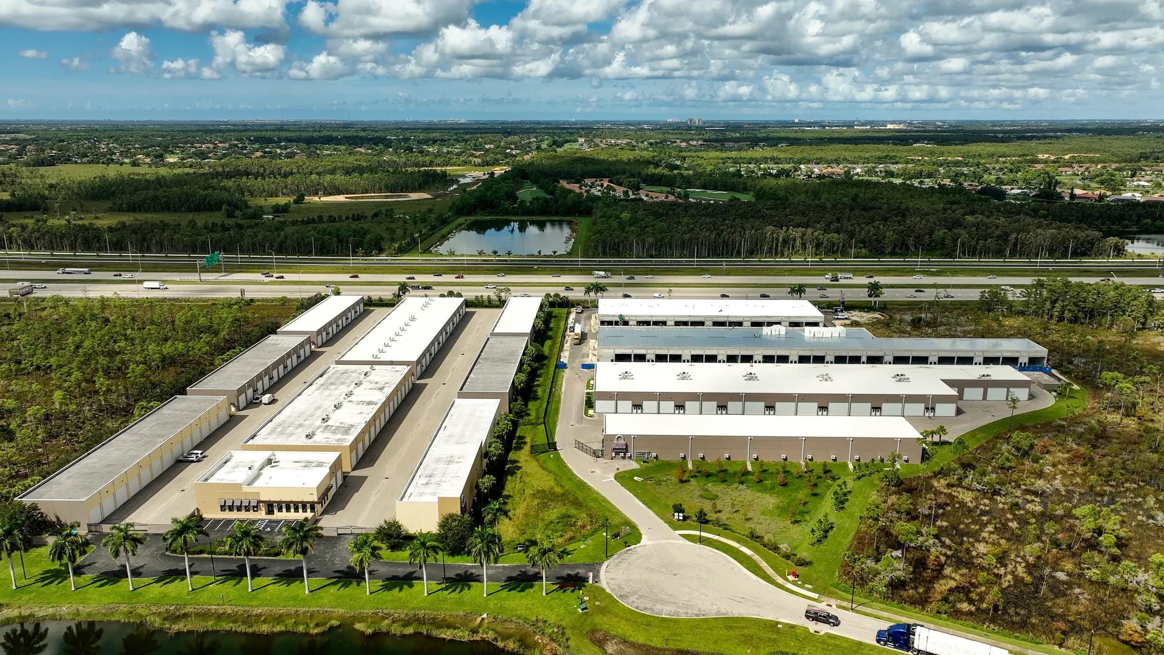 Closer aerial from the lake side showing the entrance drive and the front building rows with their white garage doors.