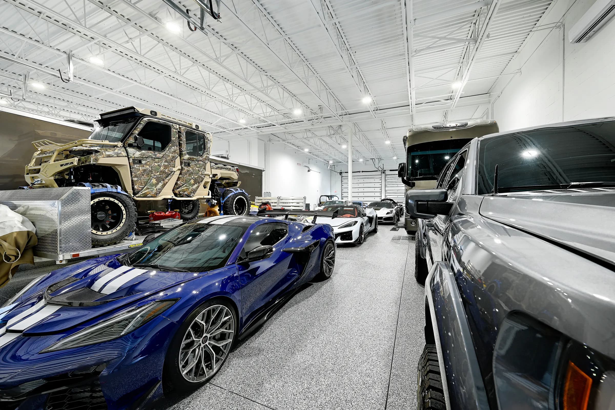 A large unit holding an off-road truck, sports cars and a motor coach under open steel trusses.