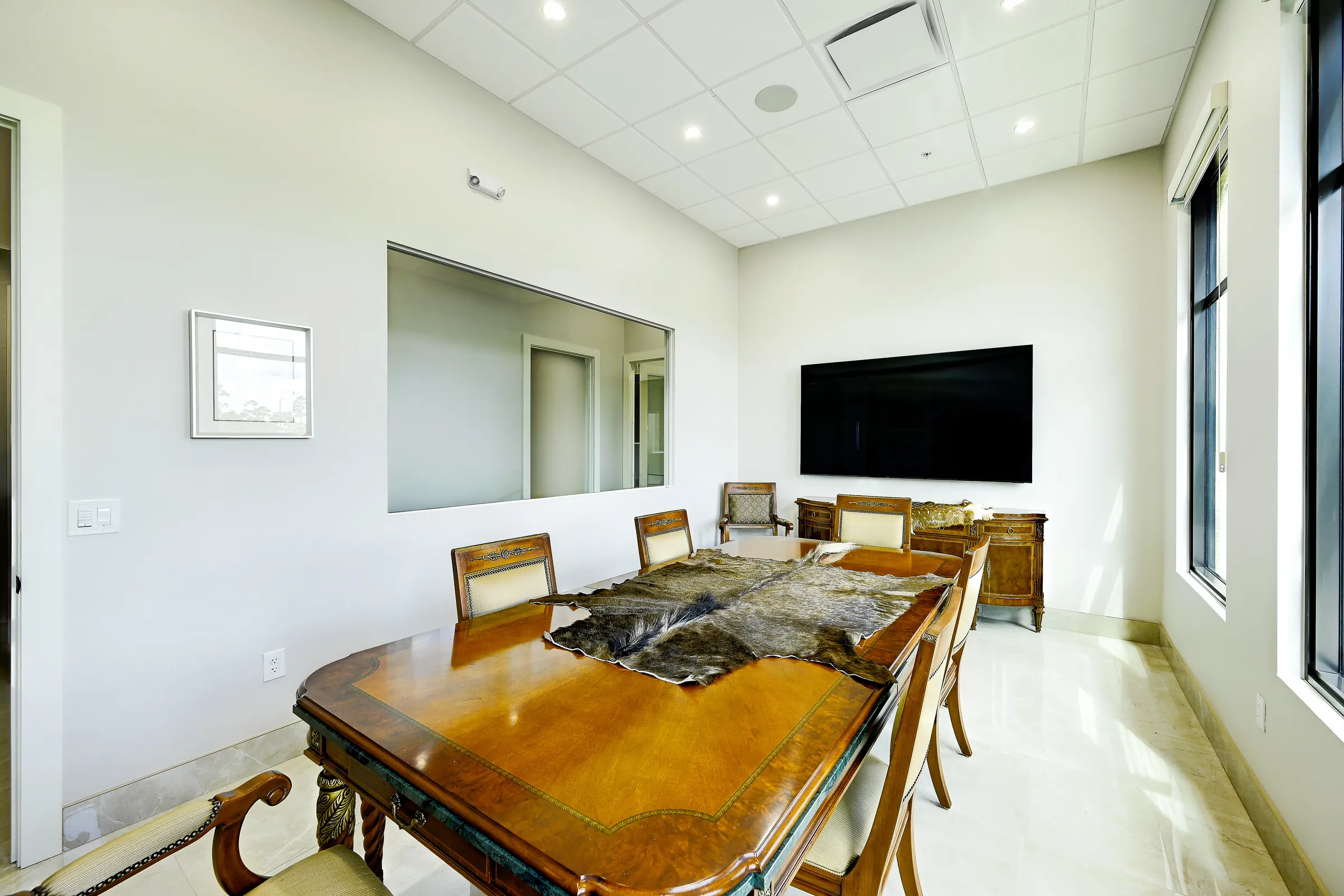 The conference room's wood table and upholstered chairs, with a wall-mounted TV.