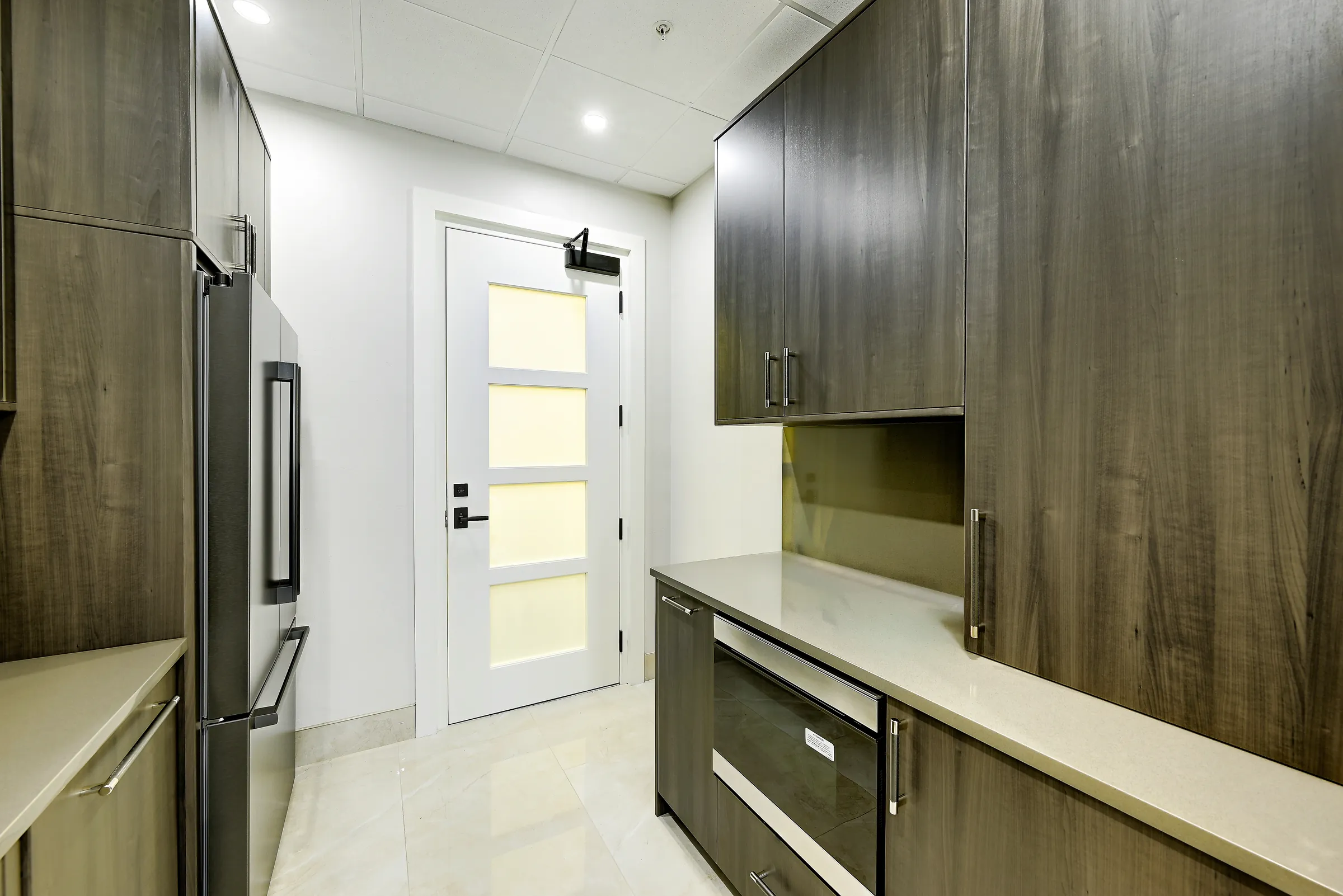 The showroom kitchen looking toward the frosted-glass door, with a beverage drawer and cabinets.