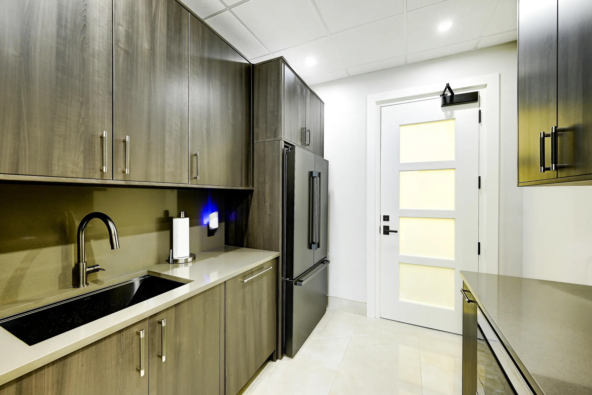 The showroom kitchen's undermount sink, black faucet and tall refrigerator.