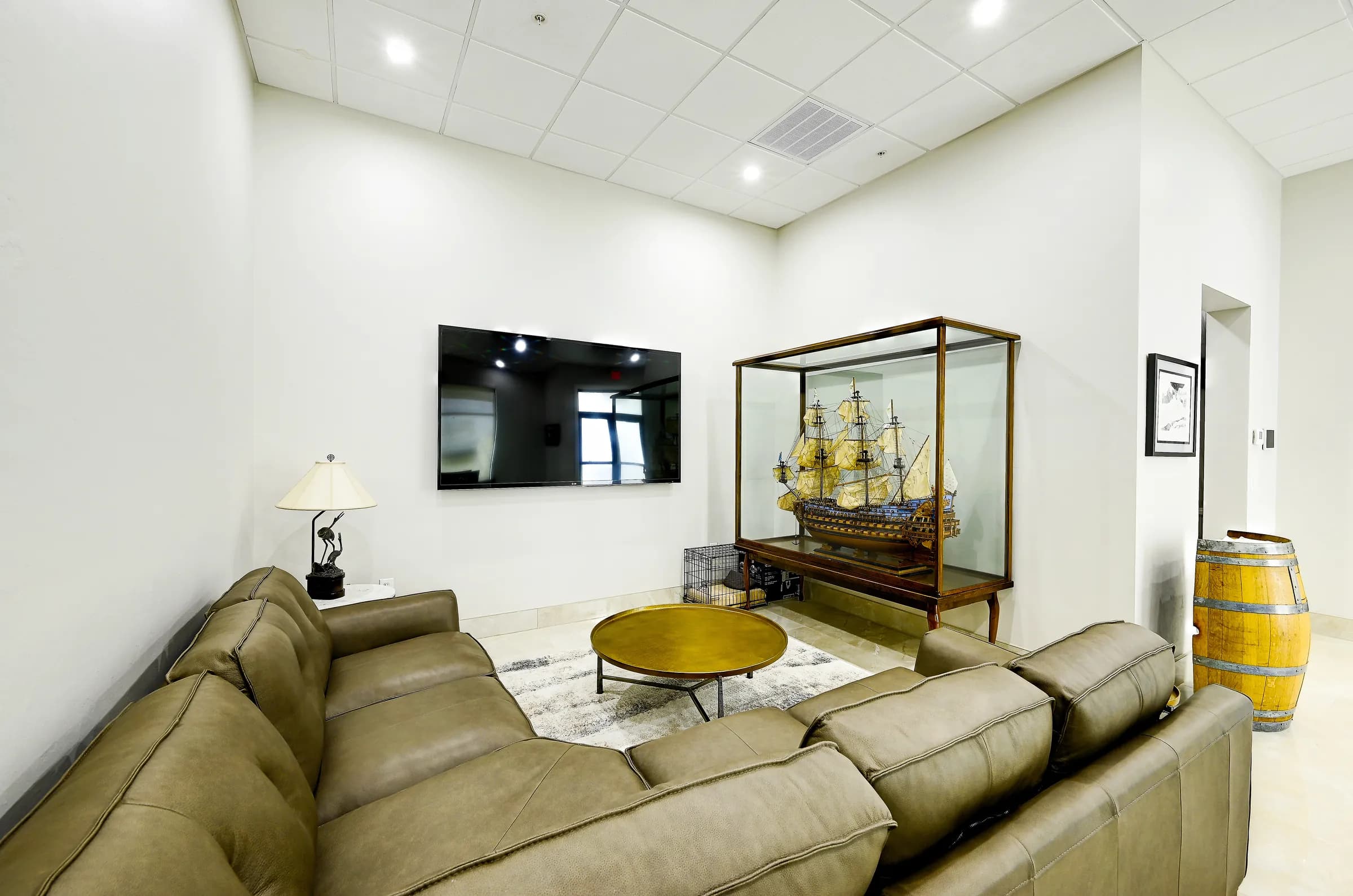 A second view of the showroom living area, with the sectional, the ship case and a wine barrel.