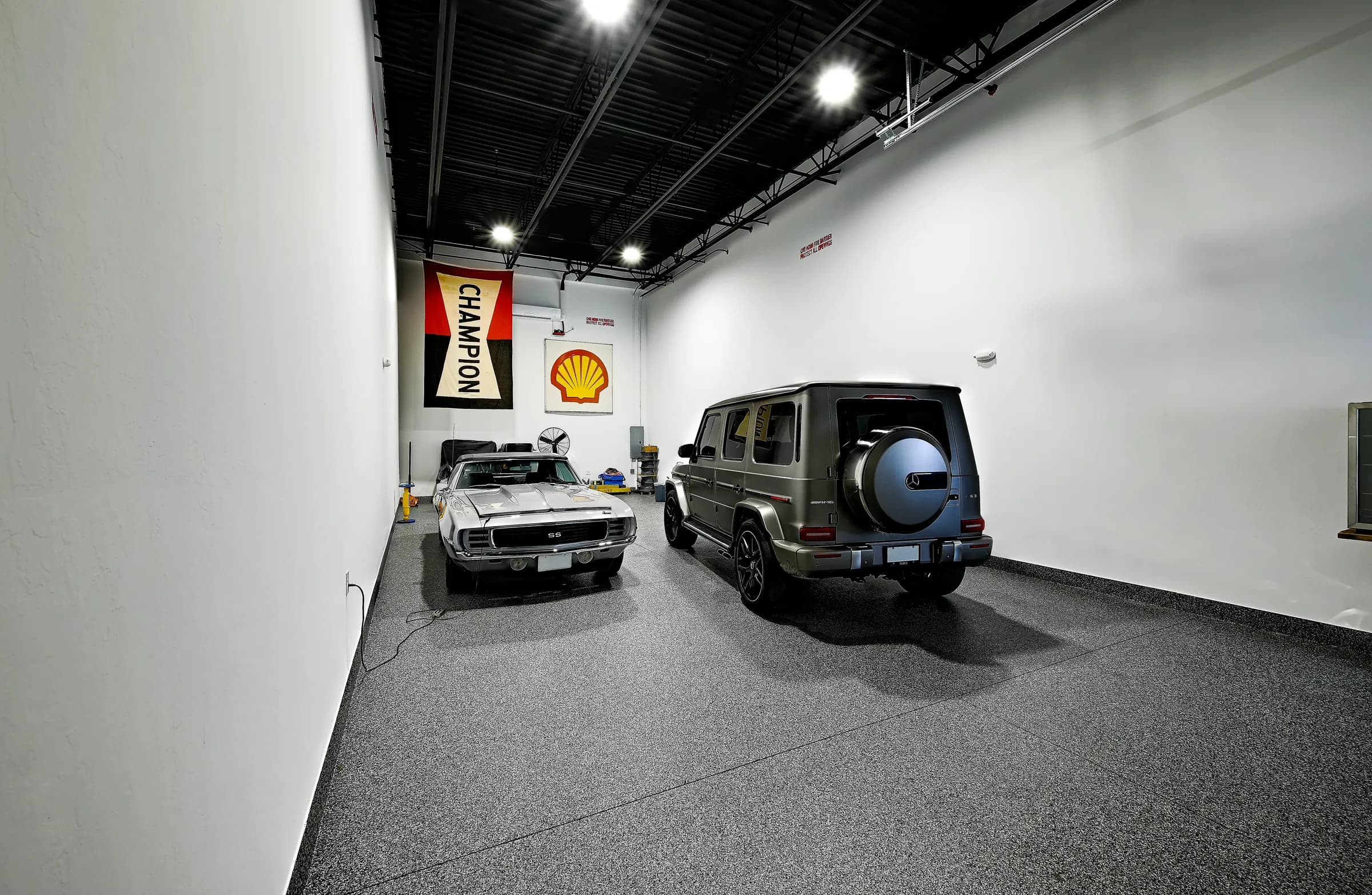 The unit's rear wall with vintage racing signs above the classic car and the SUV.