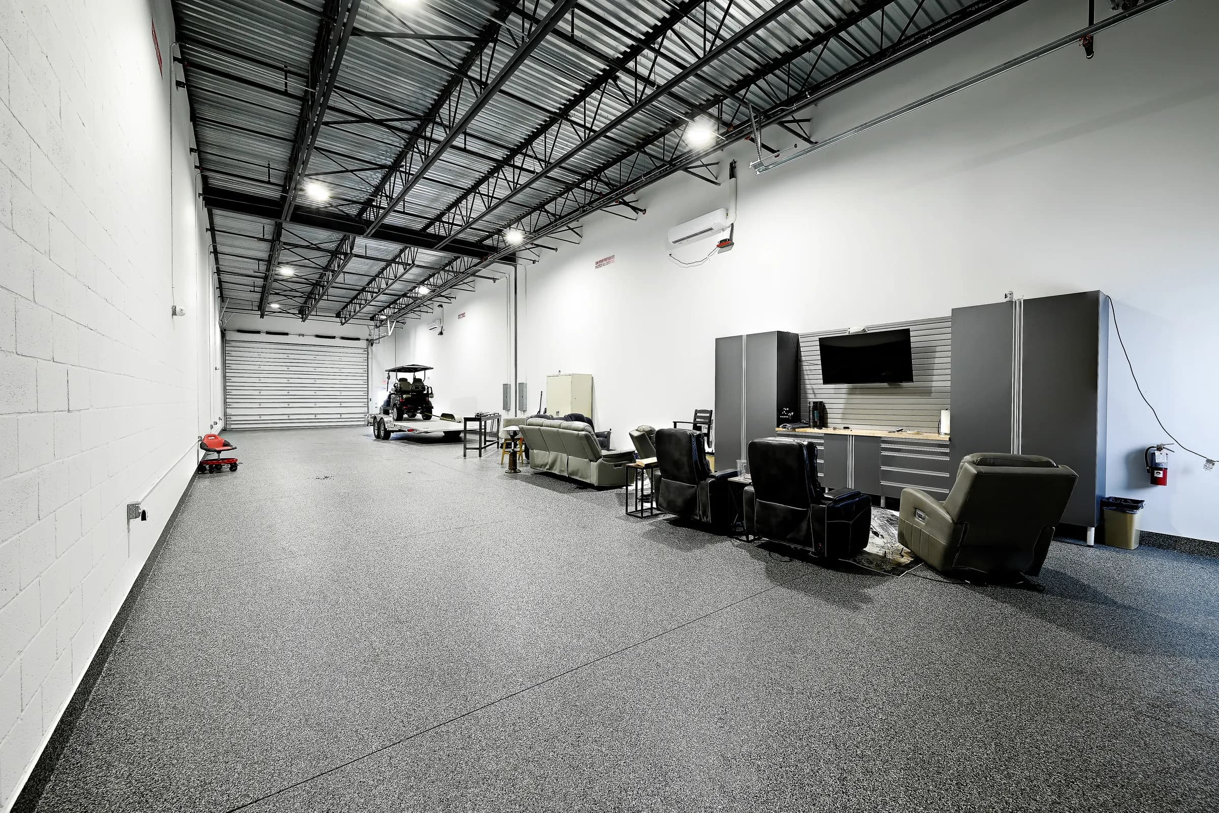 Wide view of the lounge unit, with the seating, cabinets and TV up front and a trailer at the back.