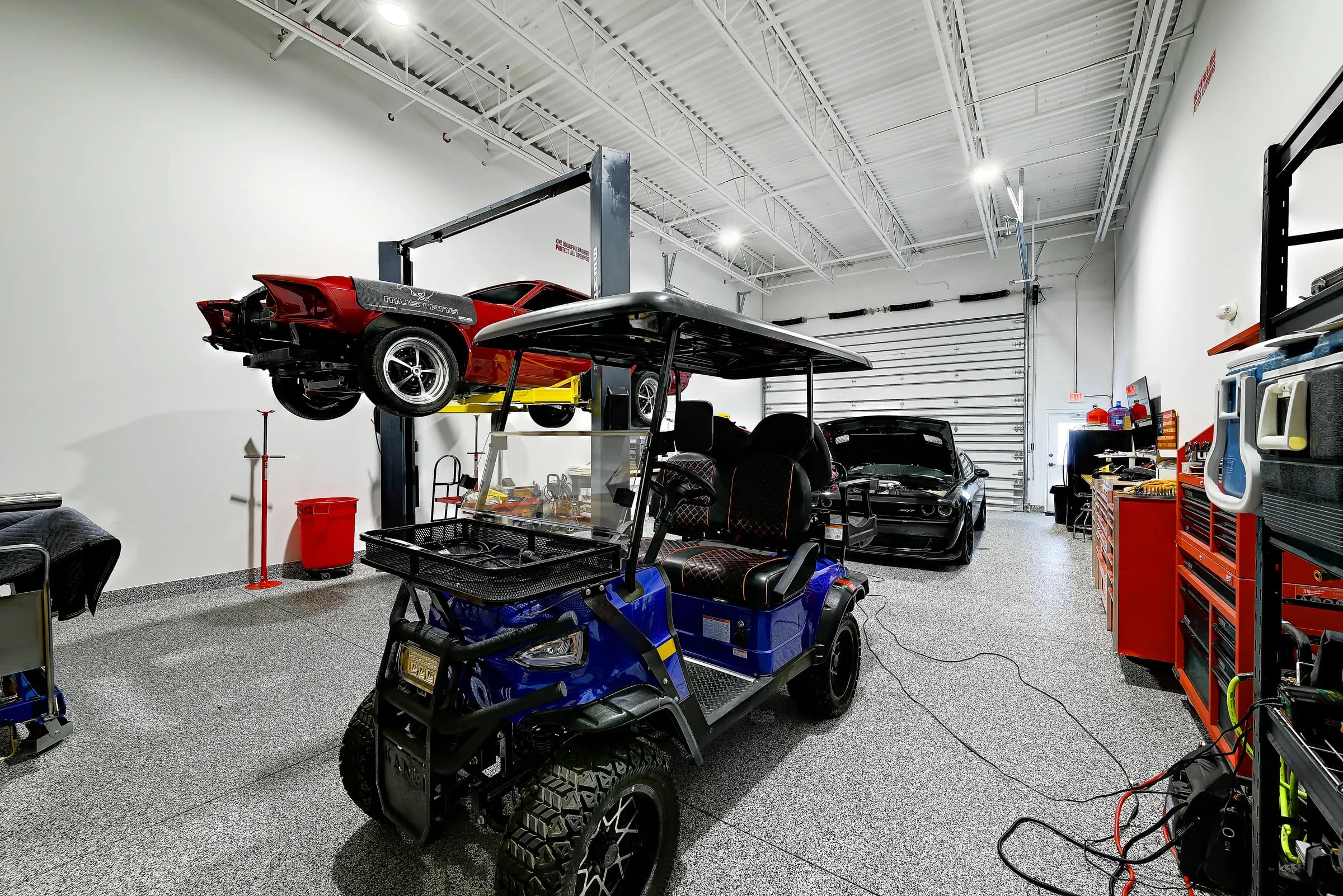 The workshop unit with a custom golf cart in front and a car on the lift behind.