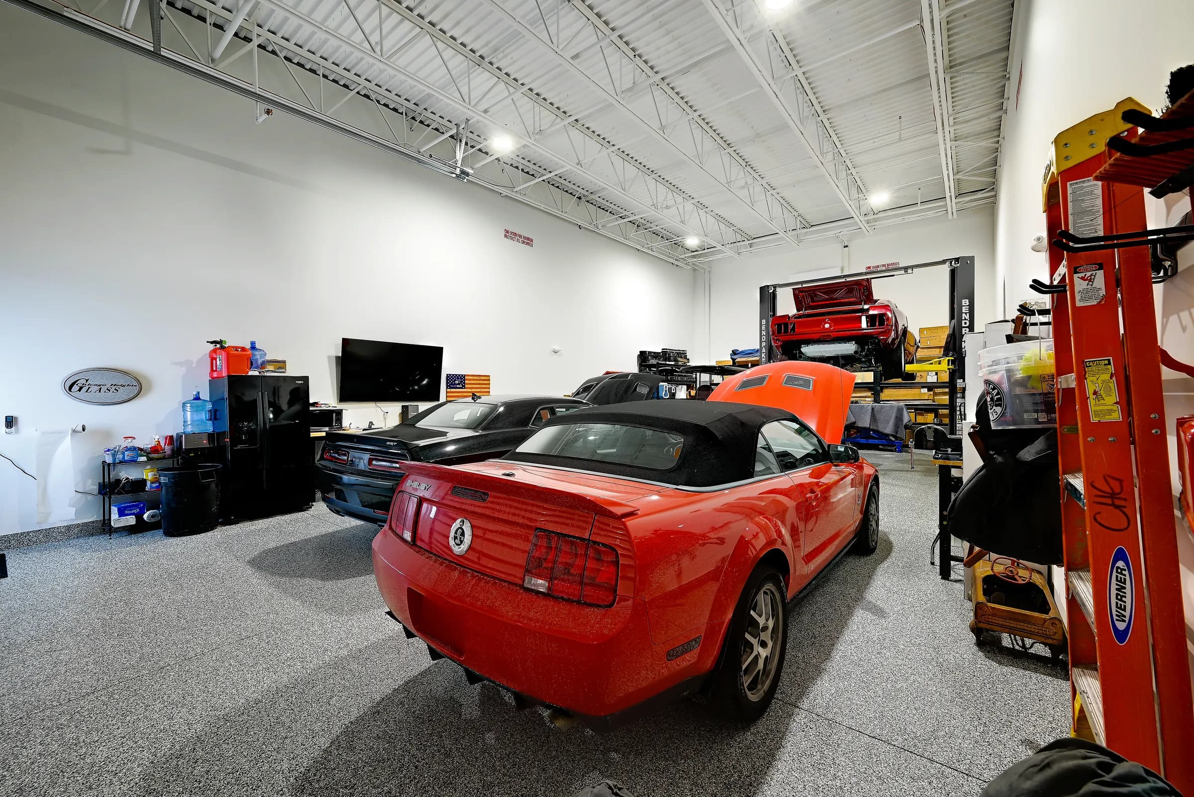 The workshop unit with a red convertible, a black coupe and a car on the lift at the back.