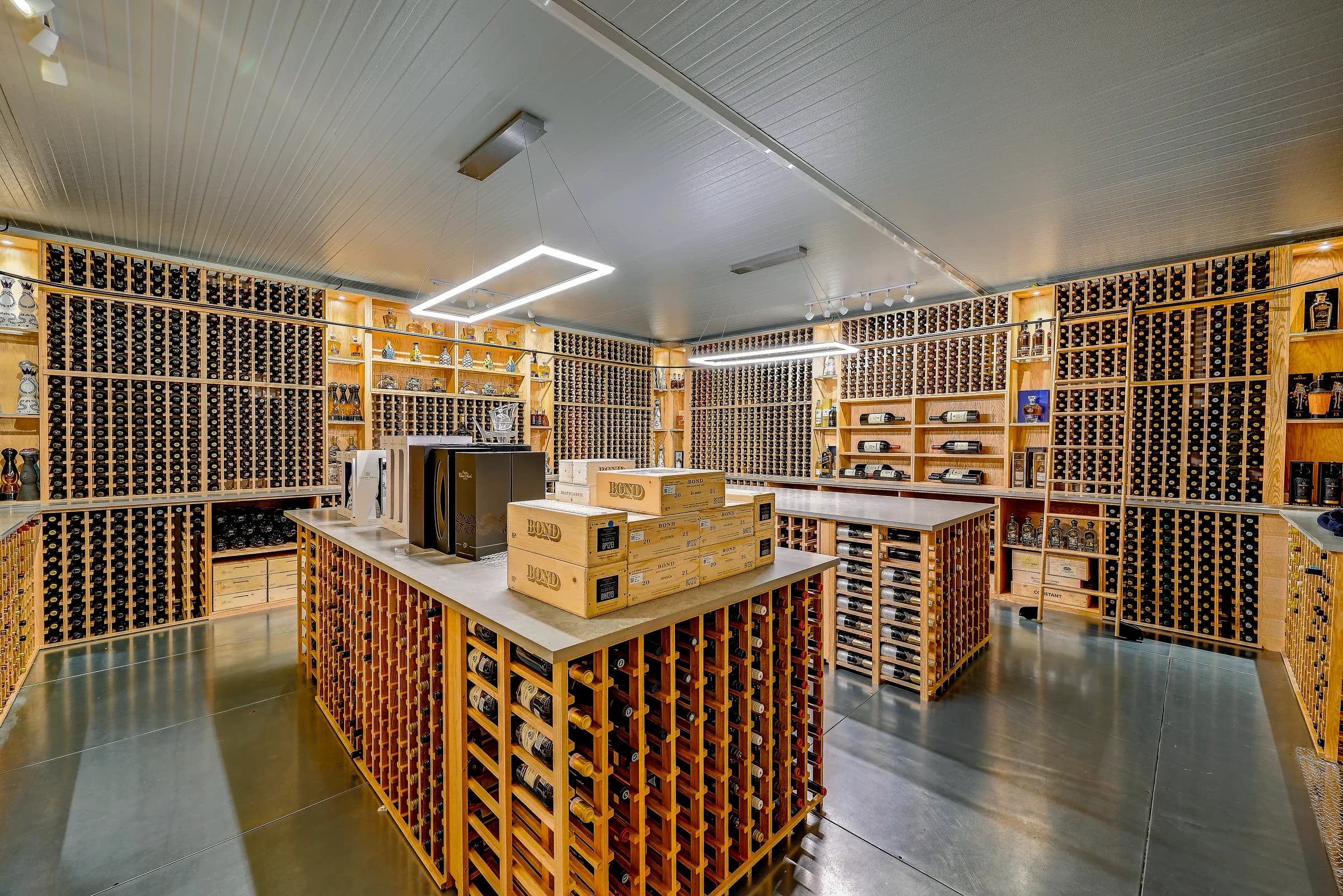 The wine cellar with full wood rack walls, a center island and wooden wine cases.