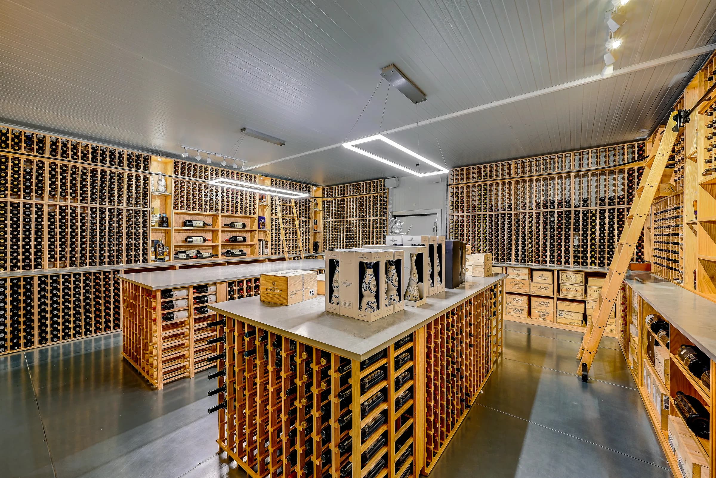 A wine cellar built inside a unit, with wood rack walls, a center island and a rolling library ladder.
