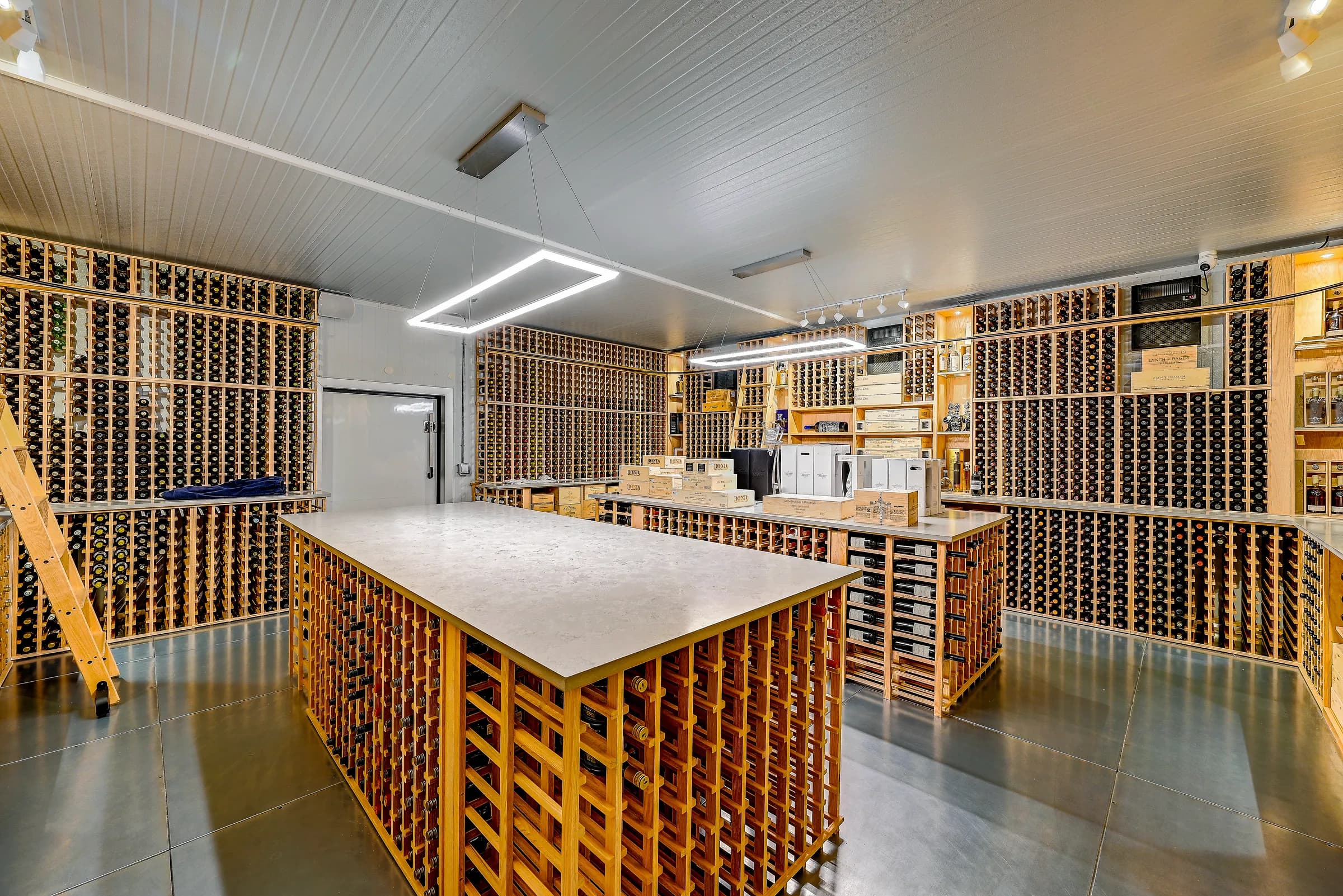 The wine cellar from the door side, with the island, rack walls and LED light frame.