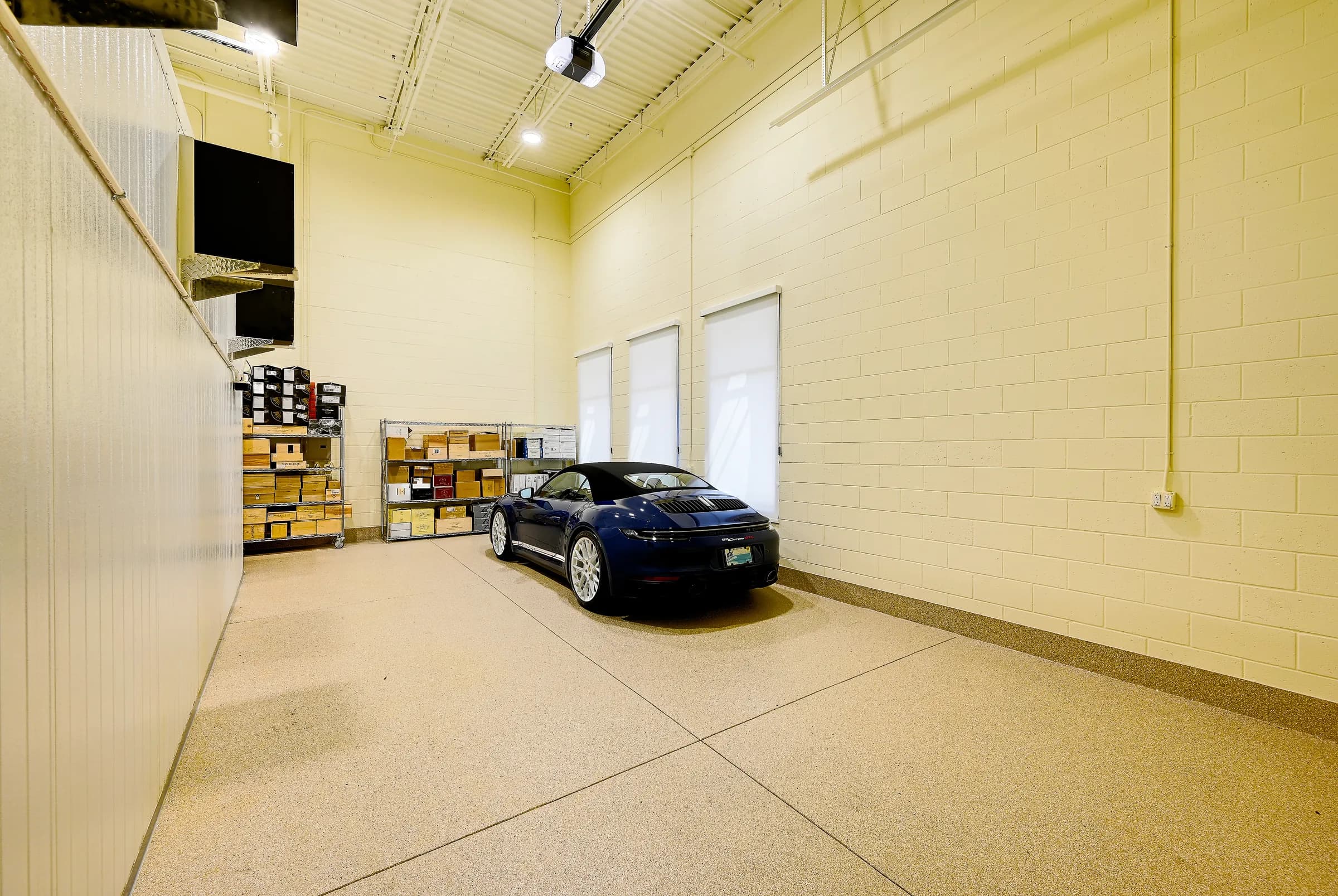 The wine unit's garage with a blue convertible and wine cases on shelves.